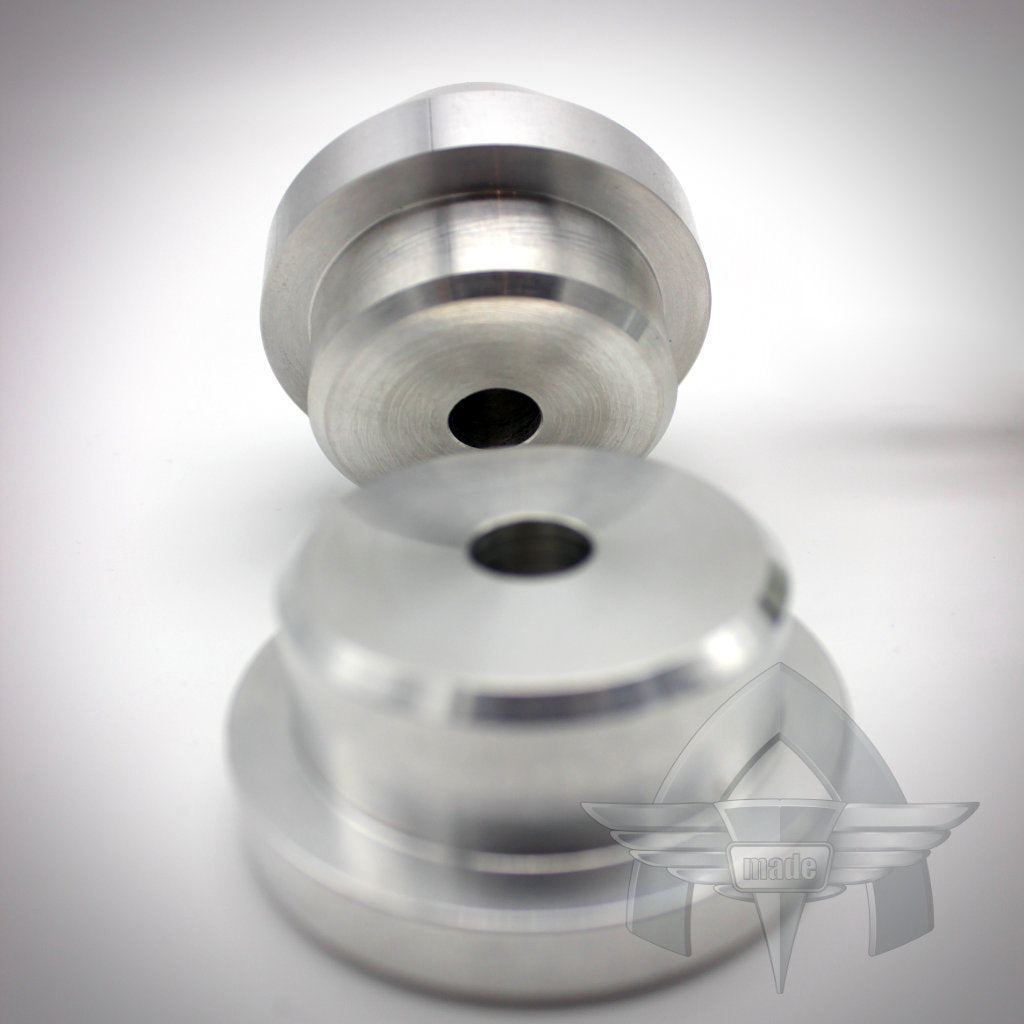 Zwei bearbeitete Metallteile mit zentralen Löchern liegen auf einer weißen Oberfläche, davor das geflügelte ATmade-Logo. Perfektes Upgrade für das 55Parts-Exklusiv: ATmade Diff-Lockdown 2.0-System von ATmade.