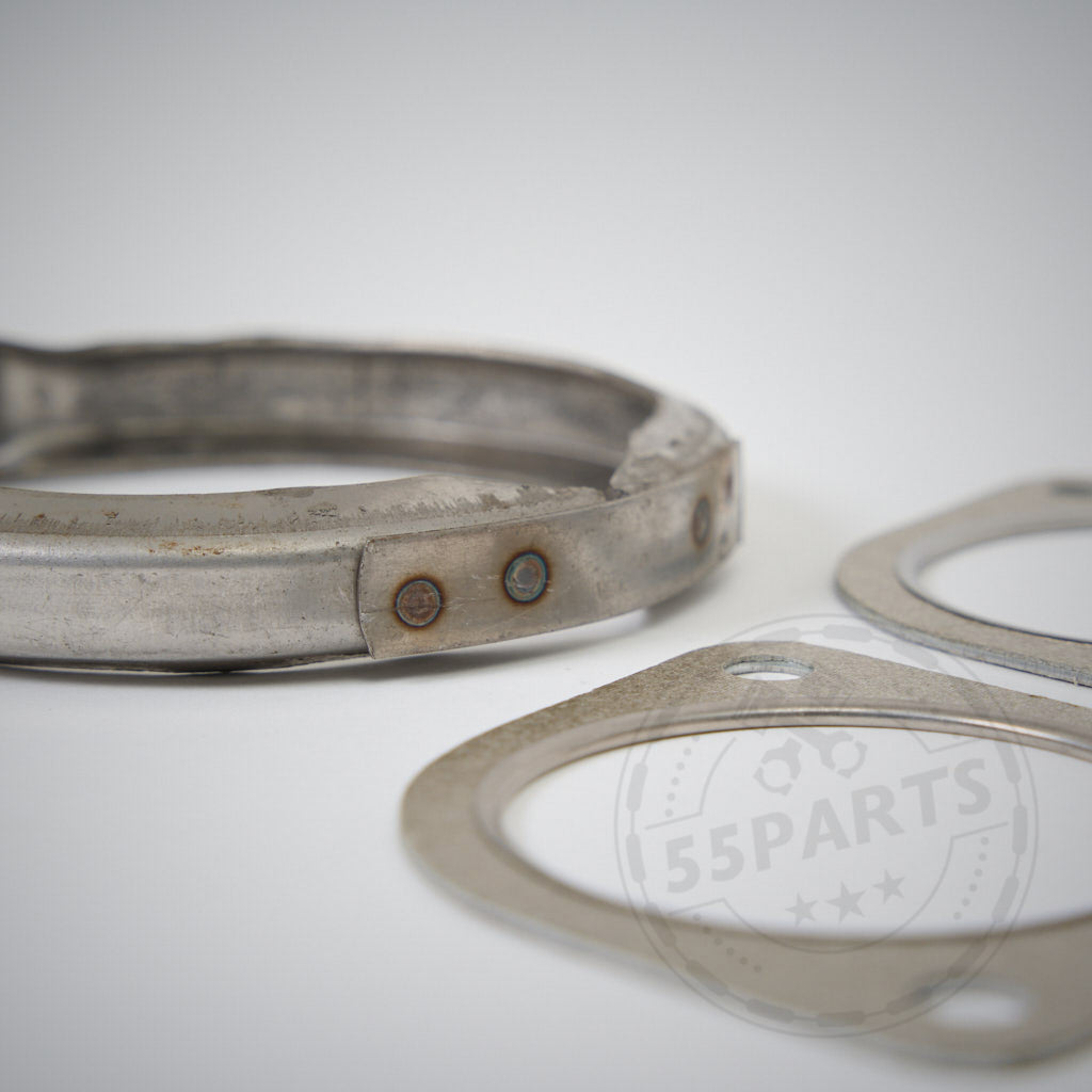 Nahaufnahme der Metalldichtungen aus dem Einbauset Downpipe-Kit passend für BMW 135i, 335i(x) N55 E-Serie, dargestellt auf einer weißen Oberfläche, wobei eine Dichtung das 55Parts-Logo trägt.
