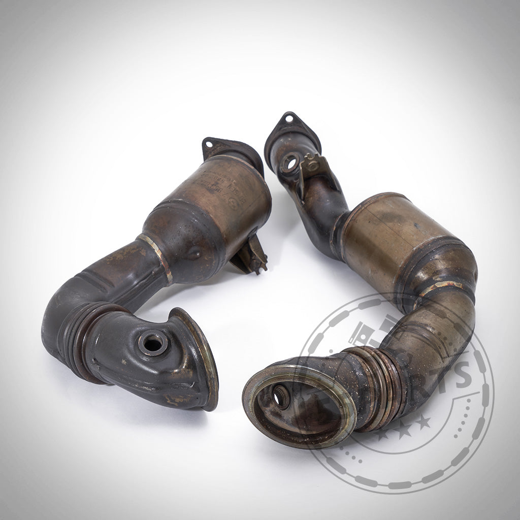 Zwei gebrauchte, umgebaute OEM-Downpipes passend für BMW 135i, 1er M Coupé und 335i N54 mit gebogenen Rohren, perfekt für FBO-Setups oder strömungsoptimierte Downpipe-Nutzung, abgebildet auf weißem Hintergrund.