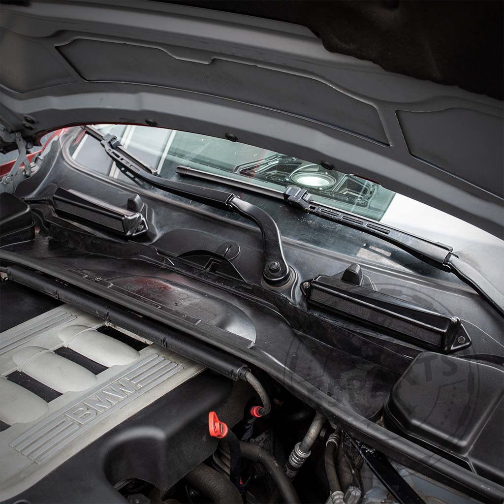 Nahaufnahme eines BMW N54/55-Motorraums mit Scheibenwischern und dem Bannik Engineering Mikrofilter Delete Gehäuse (55Parts Exclusive) passend für BMW E8x/E9x 1er und 3er Modelle in der Nähe der Windschutzscheibe.