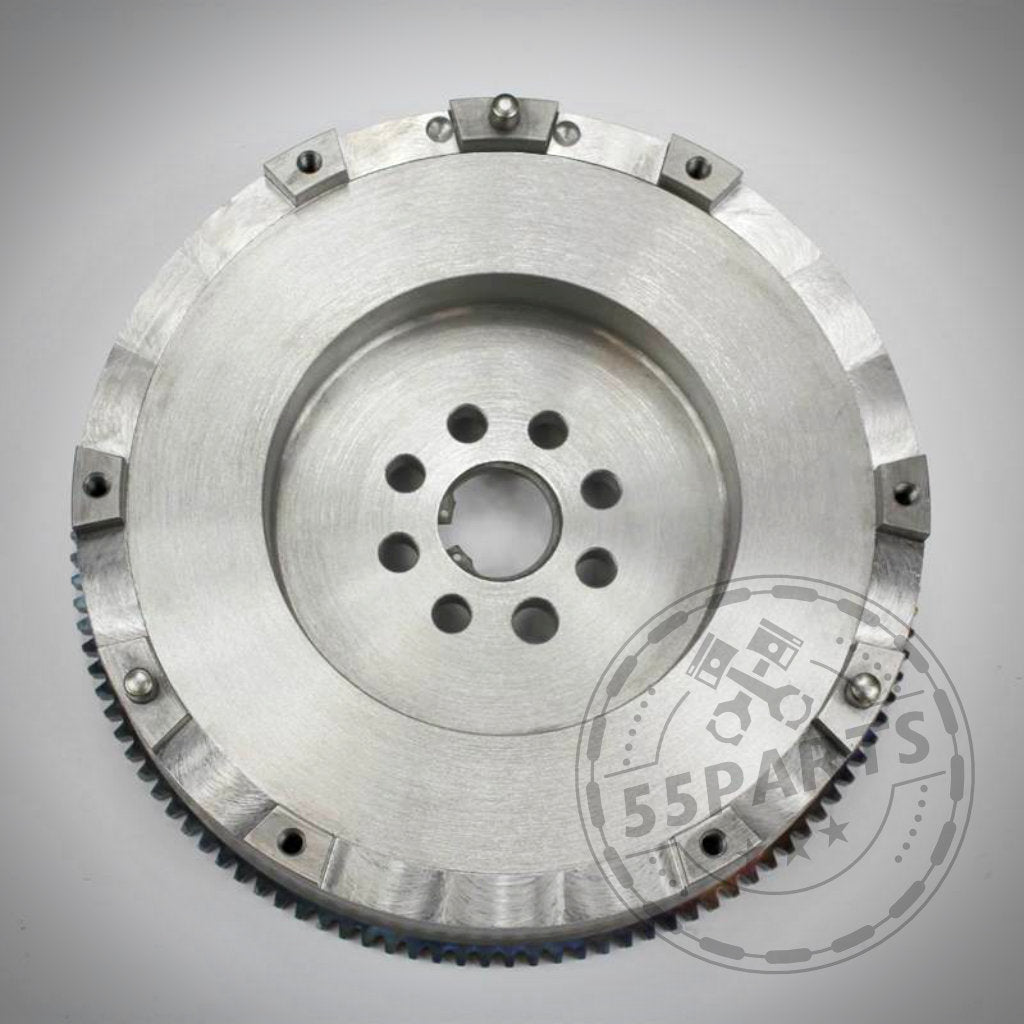 Das 55Parts Exklusive Stahl EMS inkl. gehärtetem Dorn, passend für BMW 135i, 335i(x) N54, ist ein silbernes Schwungrad mit Bohrungen und Verzahnung der Marke 55Parts, abgebildet auf weißem Hintergrund.