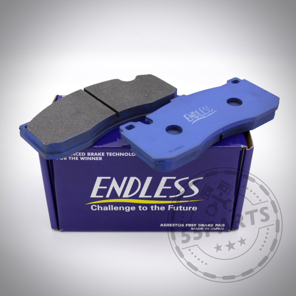 Zwei blaue Endless Bremsbeläge für 6-Kolben BMW Sattel liegen auf einer lila Endless Box mit dem Slogan „Challenge to the Future“ – ideal für BMW 135i E82, E88 Fans.