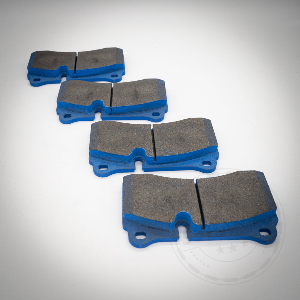 Vier Endless Bremsbeläge für 4-Kolben BMW (Performance) Sattel für den BMW M2C Hinterachse (Große Bremse) sind diagonal auf weißem Hintergrund angeordnet und demonstrieren ihre Leistung für die Rennstrecke.