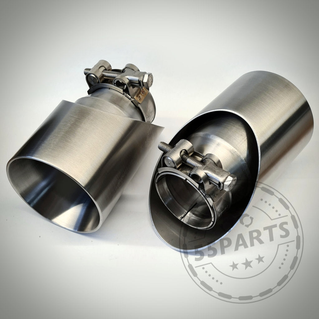 Zwei 55Parts Spezial-Endrohrblenden für F22, F23, F30-F36 x35i/x40i mit Klemmen, präsentiert auf einer hellen Oberfläche mit einem schwachen 55Parts-Logo.