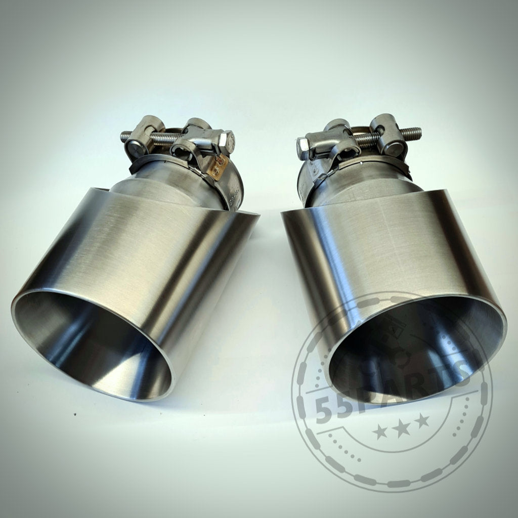 Zwei 55Parts Spezial-Endrohrblenden für F22, F23, F30-F36 x35i/x40i aus Edelstahl mit Klemmen nebeneinander auf heller Oberfläche platziert.