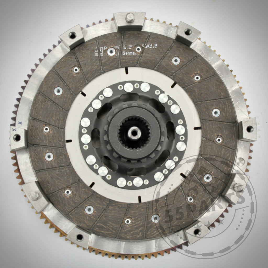 Eine Nahaufnahme der 55Parts Exklusive Zweischeibenkupplung inkl. EMS, entwickelt passend für BMW 135i und 335i(x) N54, die ihre runden Metallkomponenten und strukturierten Reibflächen für eine überlegene Kupplungslösung hervorhebt.