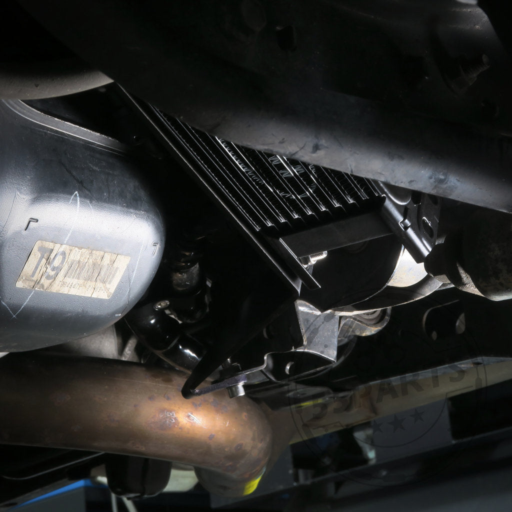 Nahaufnahme des Fahrgestells eines Toyota GR Yaris mit hervorgehobenen Metallkomponenten, Auspuffrohren, Antriebsstrang und dem HEL Performance Plug and Play Differential-Kühlungskit Hinterachse Special.