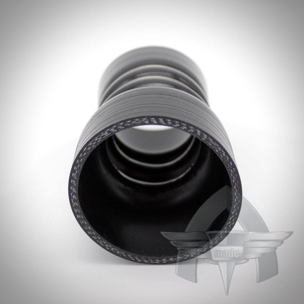 Schwarzer flexibler Silikonschlauch von ATmade, von einem Ende betrachtet, mit gerippter Innenseite und Logo-Wasserzeichen. Perfekt für die Ladeluftverrohrung oder als Teil des 55Parts-Exklusivangebots: ATmade Custom Silicone Hose Kit für FBO-Upgrades.