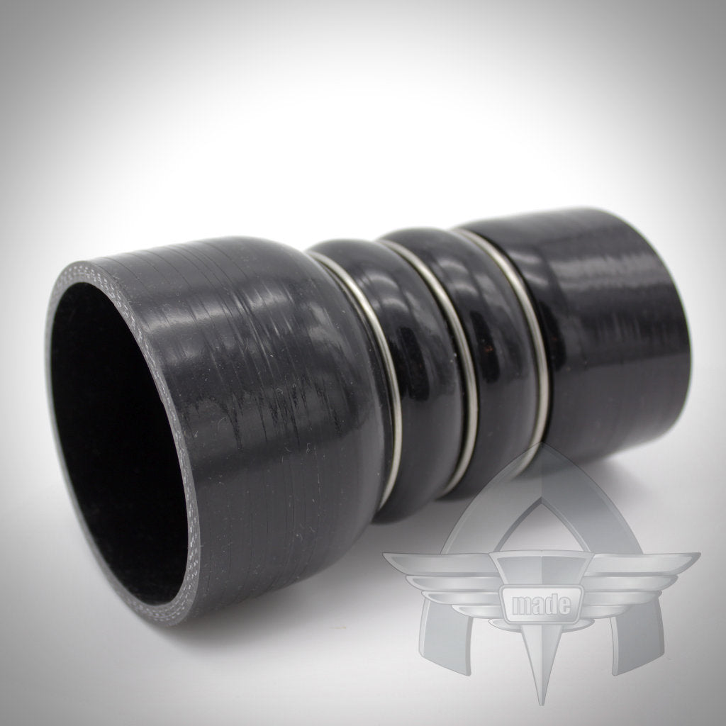 Das exklusive kundenspezifische Silikonschlauch-Kit „Ladeluftverrohrung“ von ATmade 55Parts verfügt über einen schwarzen gerippten Silikonschlauchanschluss mit zwei Metallringen, die auf einem weißen Hintergrund mit einem schwachen Logo dargestellt sind.