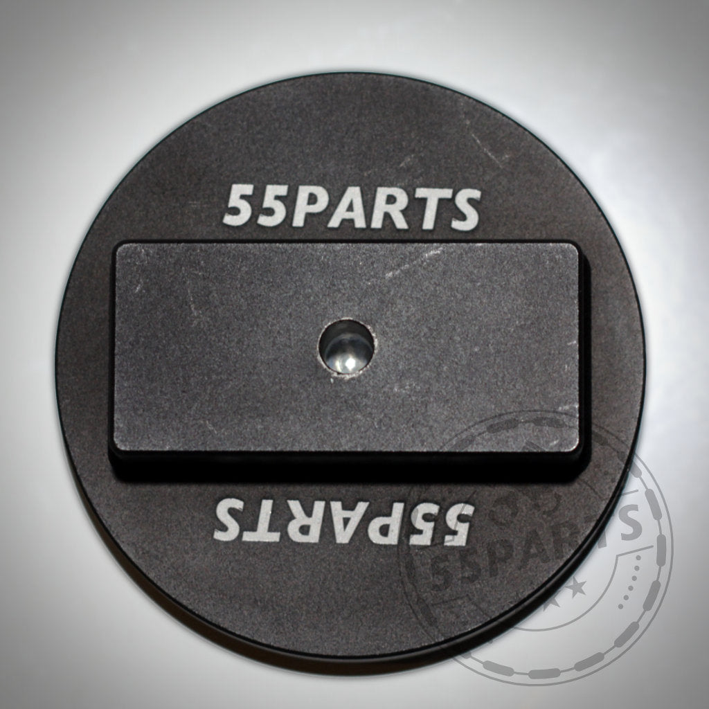 Die 55Parts Jackpad Wagenheberadapter Anhebehilfe Aufbockhilfe passend für BMW ist ein runder, schwarzer Metalladapter mit zentralem Loch und rechteckigem Absatz, präzise CNC-gefräst für optimalen Halt beim Anheben.