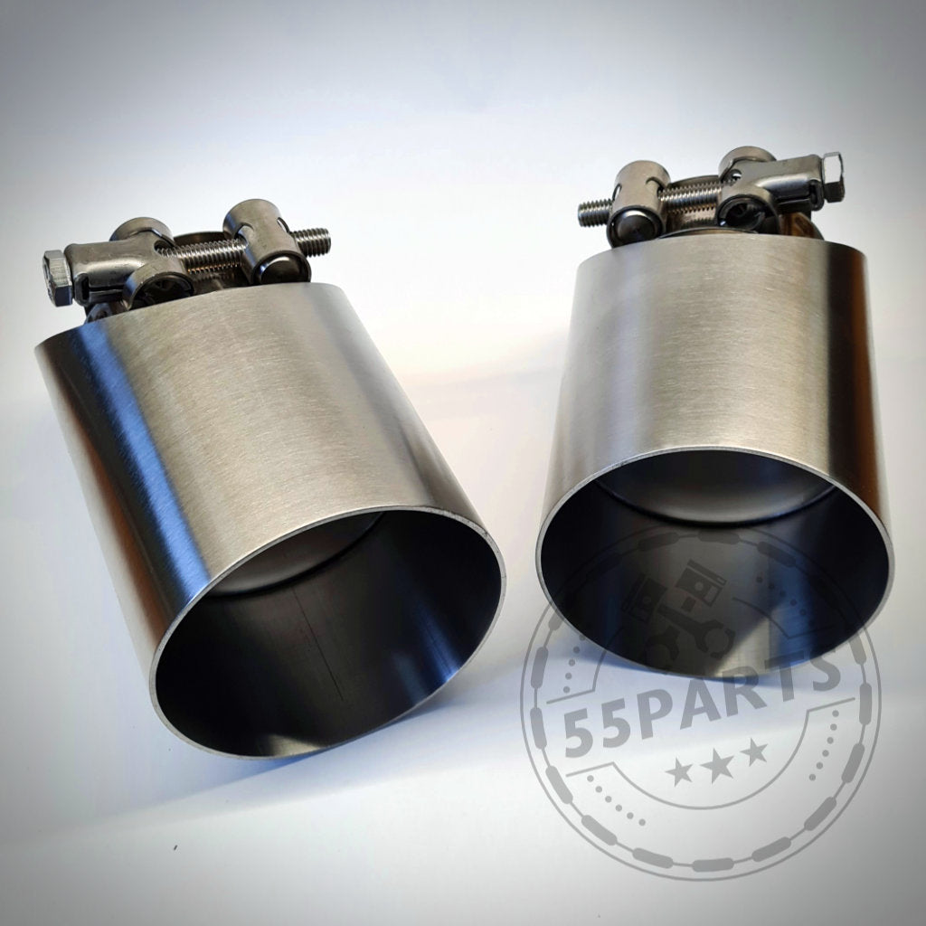 Zwei 55Parts Spezial-Endrohrblenden für F20/F21 M140i B58 werden nebeneinander mit Klemmen auf weißem Hintergrund präsentiert.