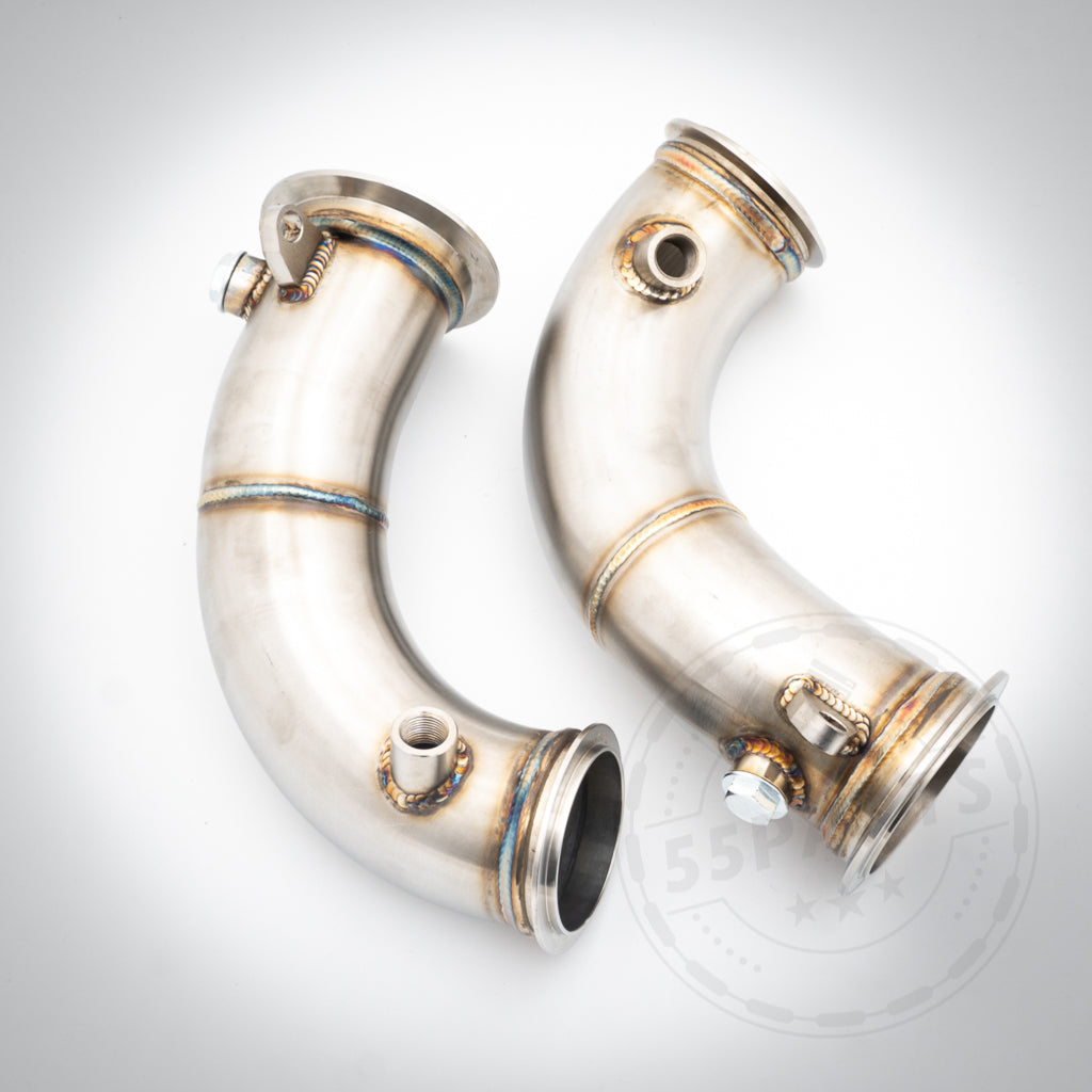 Die 55Parts Catless Katlose-Downpipes passend für BMW M5/M5 Competition F90 S63 verfügen über Schweißverbindungen und Gewindeanschlüsse, sind ideal für FBO-Setups und werden metallisch und gebogen auf weißem Hintergrund dargestellt.