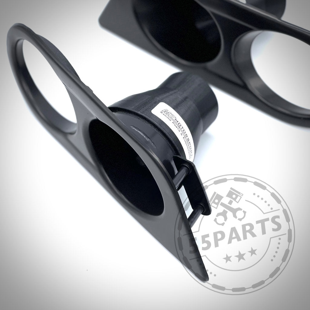 Das 55Parts Exclusive Bremsbelüftungsset, in Nahaufnahme mit zwei runden Öffnungen und einem Rennstrecken-Logo abgebildet, ist ein schwarzes Kunststoff-Autoteil, das sich ideal für BMW E46-Modelle (einschließlich M3) mit Serienbremsanlagen oder BMW-Bremssystemen eignet.