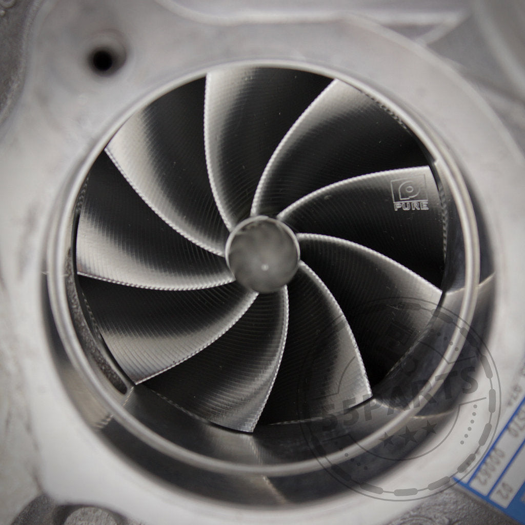 Nahaufnahme eines Pure Stage 2 Upgrade-Turboladers von Pure Turbos mit einem Kompressorrad aus Metall mit gebogenen Schaufeln und eingraviertem Logo, entwickelt passend für BMW (M)135i, M235i, 335i(x) und 435i(x) mit N55-Motoren.