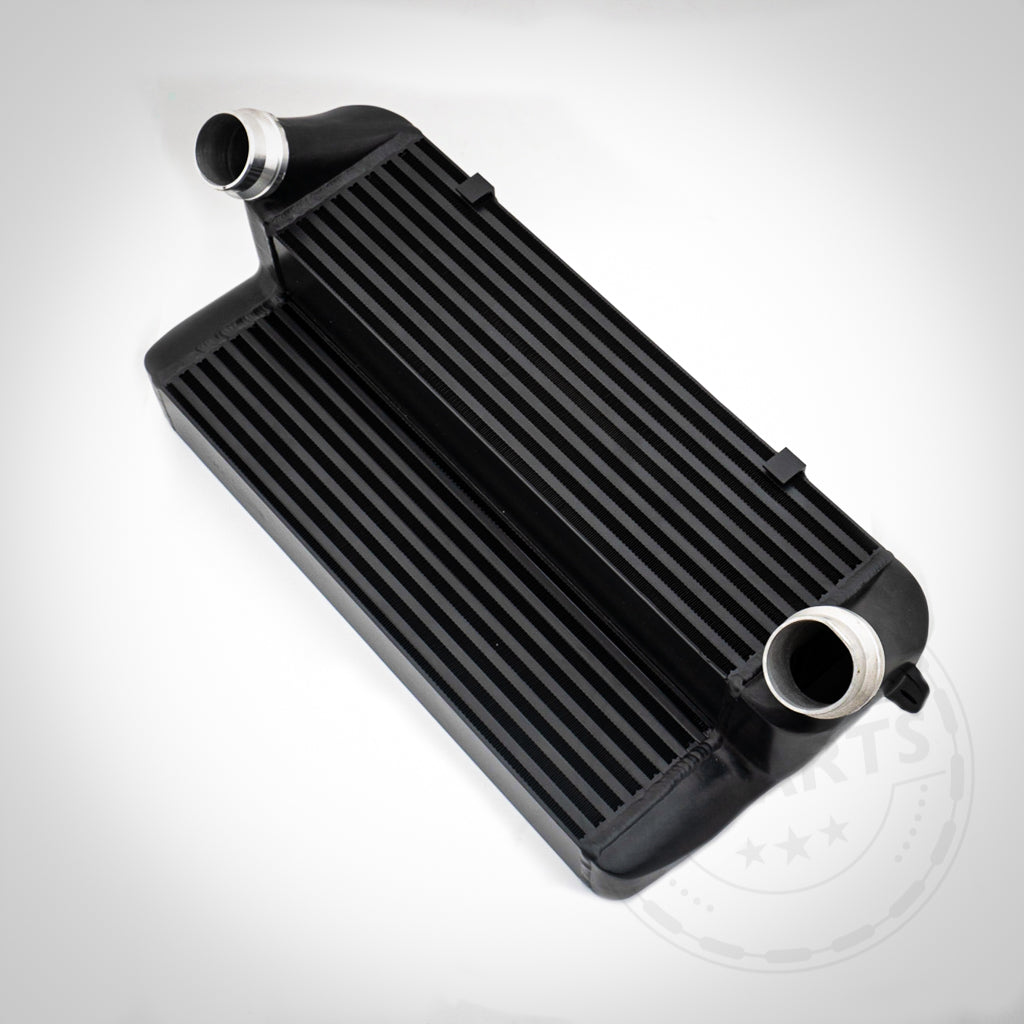 Der 55Parts 7" Race Ladeluftkühler passend für BMW F2x, F3x, F87 (M135i, M235i, 335i, 435i, M2 N55 F-Serie) verfügt über eine schwarze gerippte Oberfläche und zwei silberne Einlass-/Auslassrohre. Komplett anschraubbar. Inklusive Zertifikat. Auf weißem Hintergrund dargestellt.