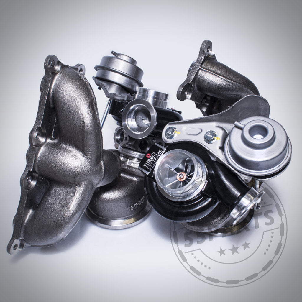 Eine Nahaufnahme eines glänzenden Turbosystems-Upgrade-Turboladers passend für BMW 135i, 1er M Coupé, 335i(x), Z4 35I(S) N54 mit Auspuffkrümmern auf weißem Hintergrund, der die fortschrittliche Turbosystems-Technik hervorhebt.