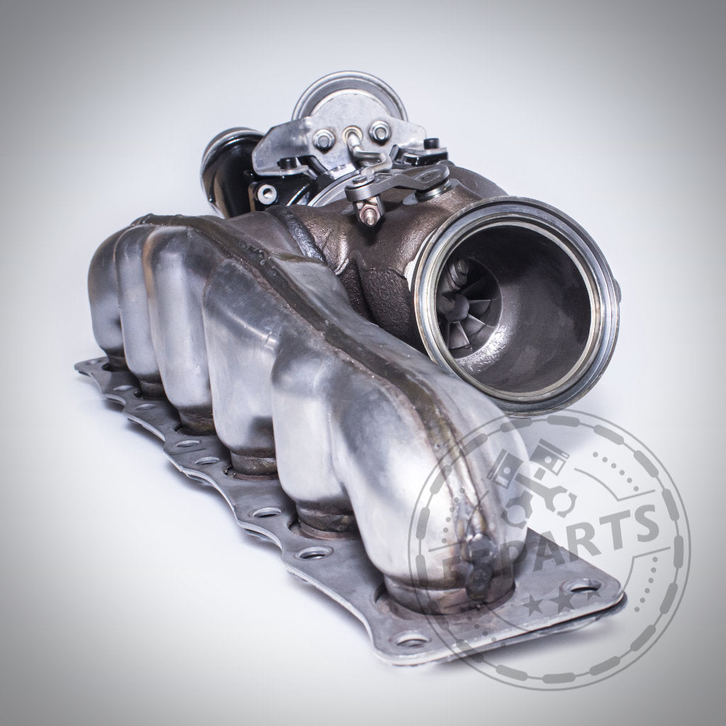 Der Turbosystems Upgrade Turbolader passend für BMW (M)135i, M235i, M2 F87, 335i(x), 435i(x) und 535i(x) N55 ist mit angebautem Abgaskrümmer auf hellgrauem Untergrund abgebildet – perfekt für Ihr nächstes Turbo-Upgrade.