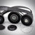 Nahaufnahme des 55Parts Riementrieb-Komplettkit-Reparatursatzes passend für BMW 135i, 335i(x) N55 E-Serie. Zu sehen sind drei schwarze Riemenscheiben, ein mehrrippiger Riemen, ein Riemenspanner und zwei schwarze Kappen.