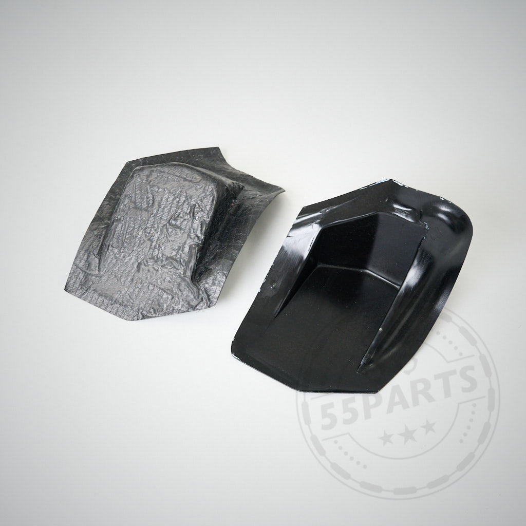 Auf einer hellgrauen Oberfläche liegen zwei schwarze Kunststoff-Verstärkungsplatten für F87 M2, M2 Competition und M2 CS – eine mit strukturierter Oberfläche, die andere glänzend –, die für die Montage eines Heckspoilers oder Heckflügels vorgesehen sind.