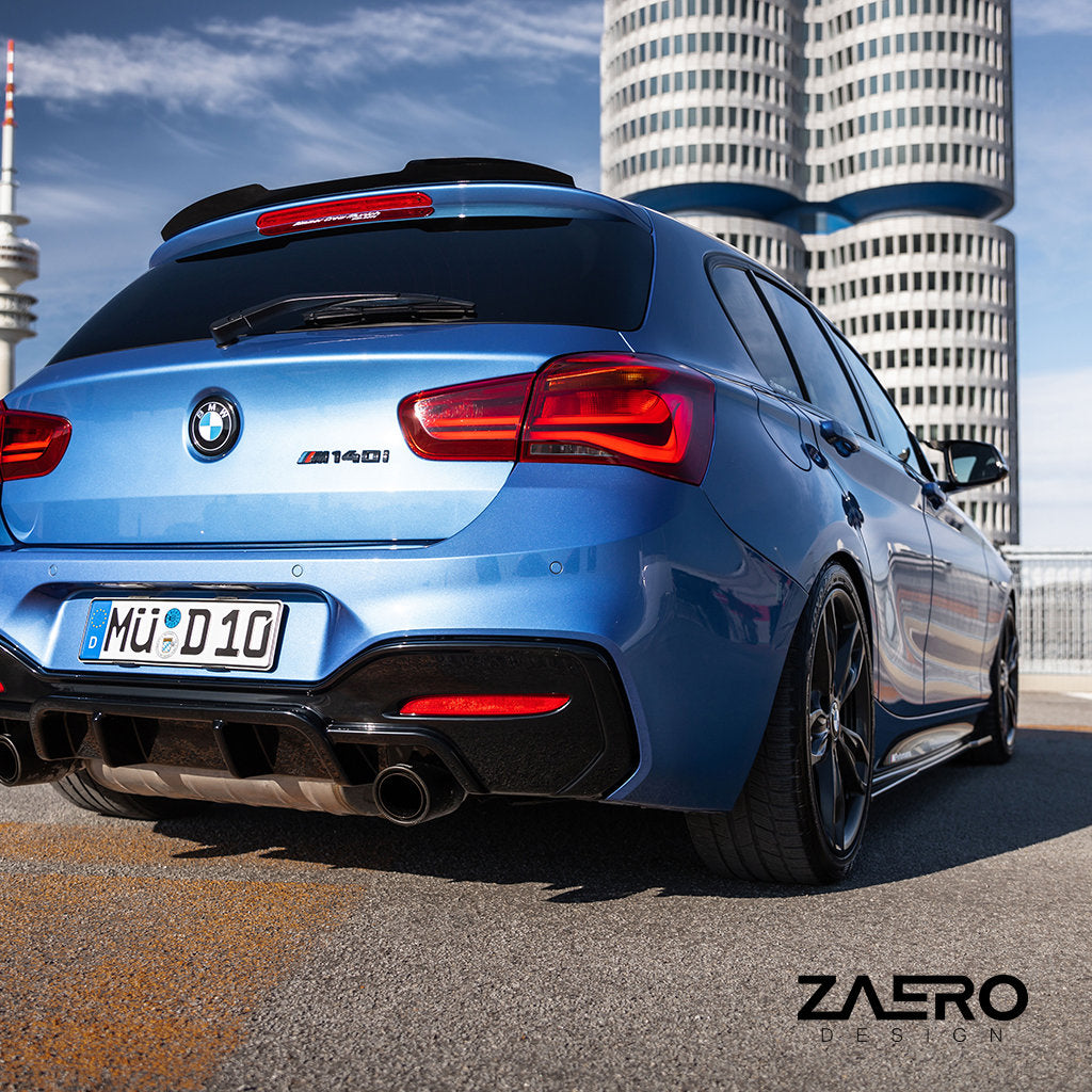 Ein blauer BMW M140i mit Carbon-Karosserieteilen und einem ZAERO Evo-1 Diffusor passend für BMW M135i/M140i F2x parkt auf einer Stadtstraße, im Hintergrund moderne Gebäude.
