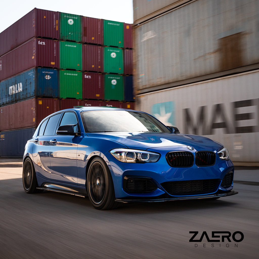 Ein blauer BMW F2x mit einem ZAERO Evo-1 Frontspoiler in Glanz Schwarz fährt an gestapelten Schiffscontainern vorbei, in der Ecke prangt das ZAERO-Logo.